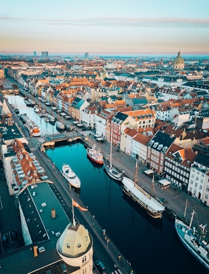 Färgglada hus och båtar längs en kanal i en stad, troligen Nyhavn i Köpenhamn, Danmark.