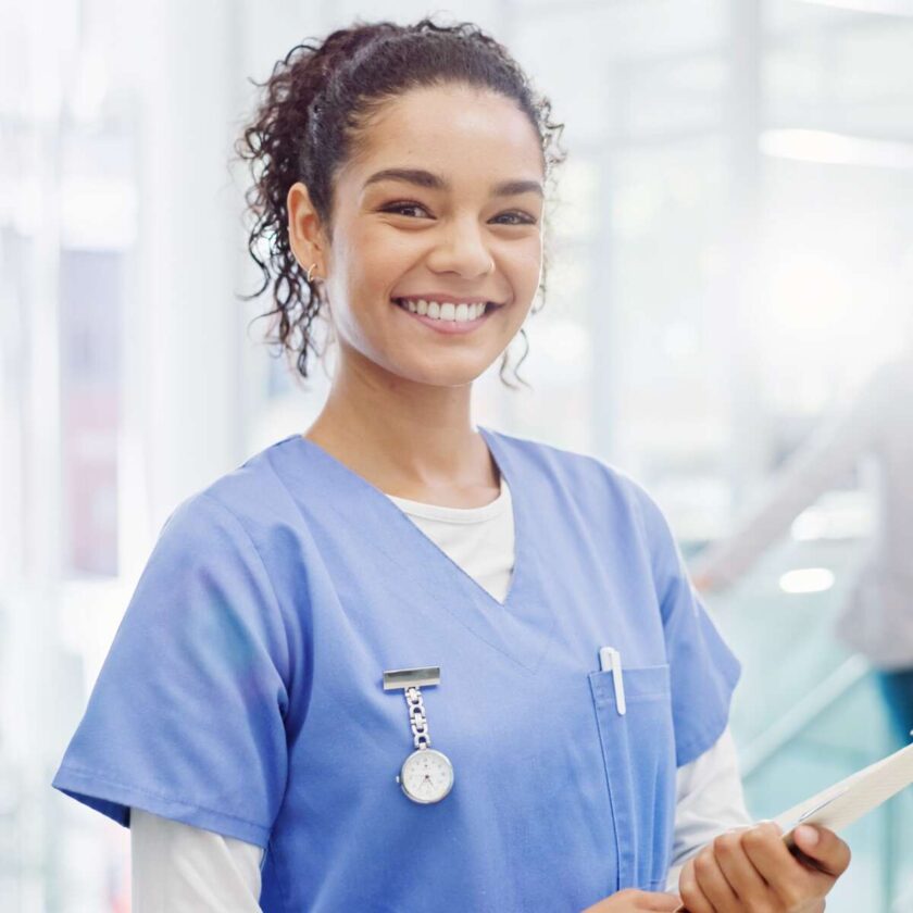 Glad sygeplejerske smilende holder patientpapirer på hospitalet
