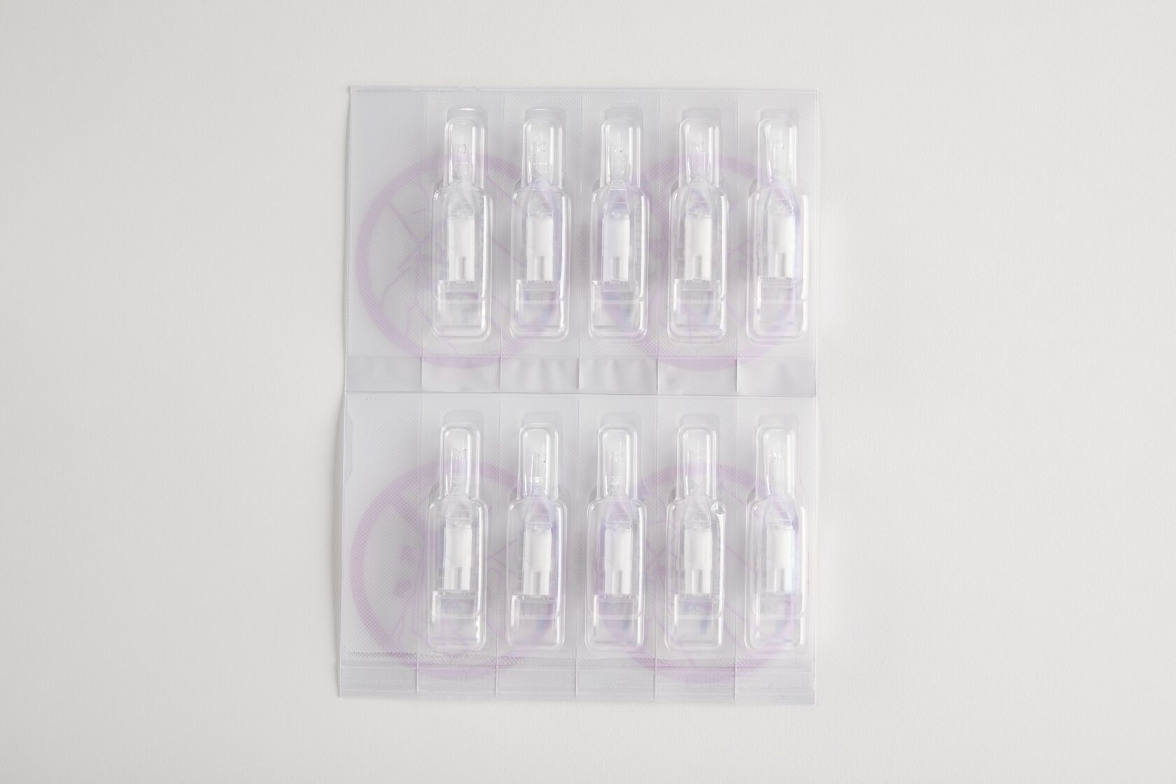 Ti pakker med engangsmedicampuller i gennemsigtig plastikemballage på hvid baggrund.
