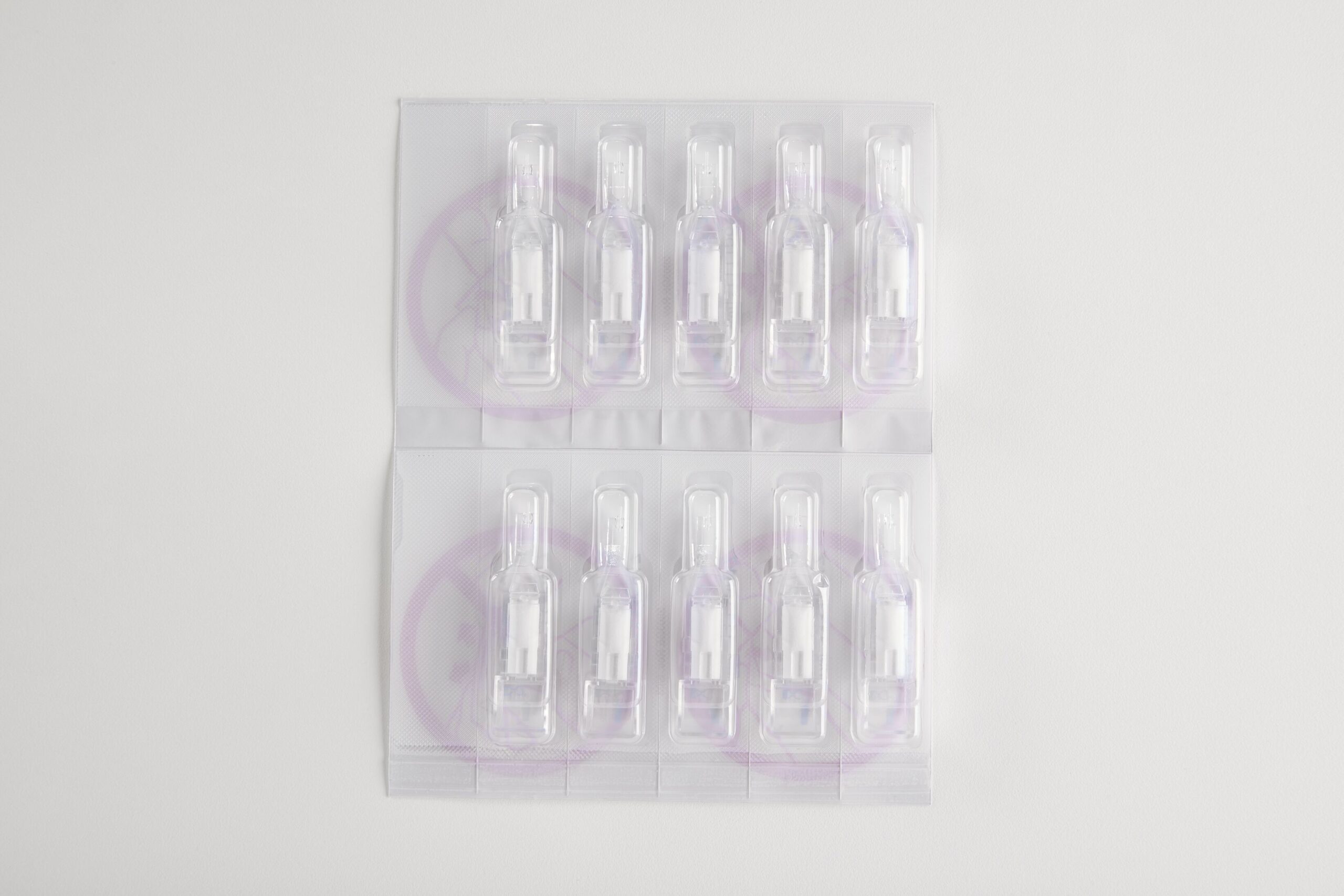 Ti pakker med engangsmedicampuller i gennemsigtig plastikemballage på hvid baggrund.