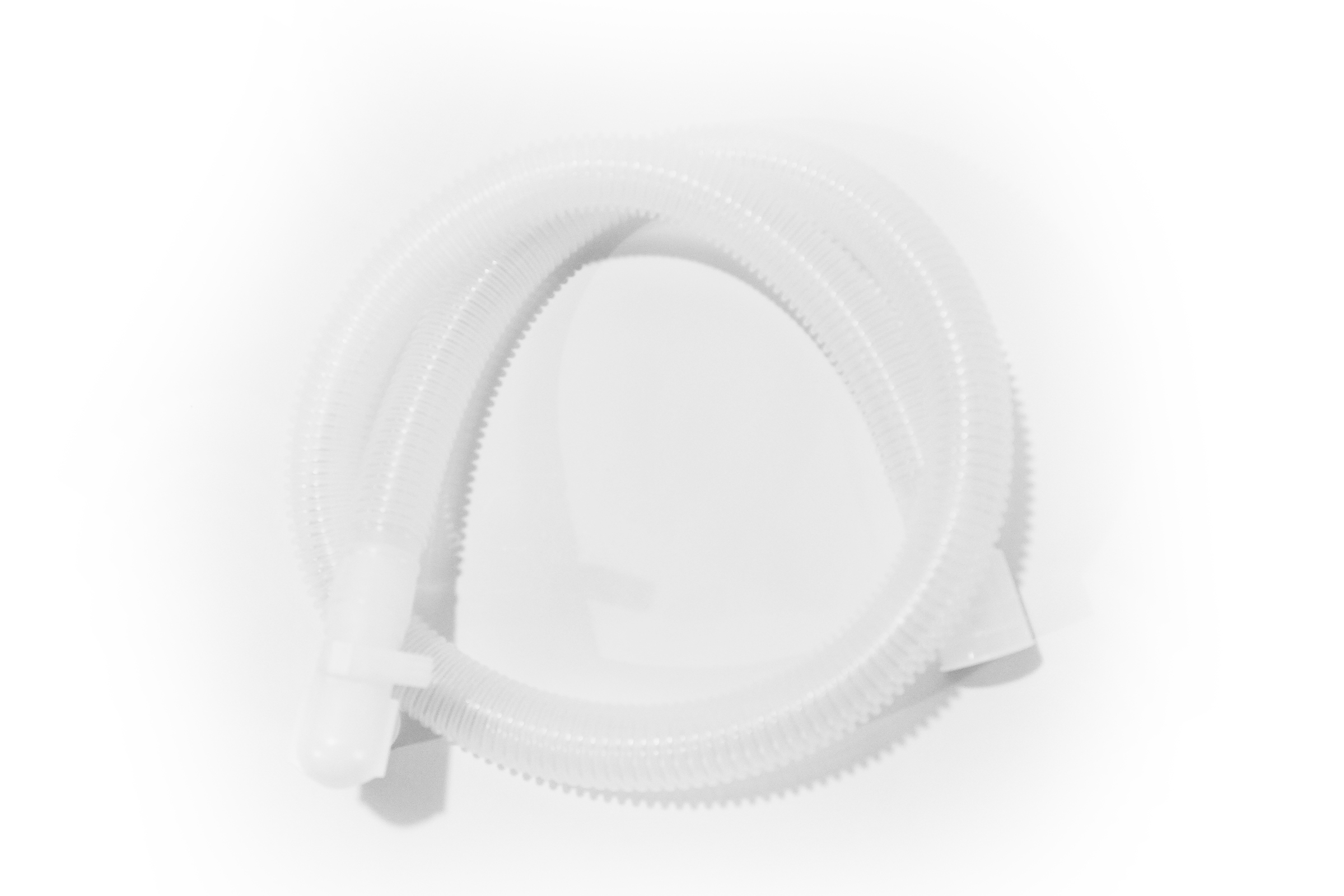 Snoet gennemsigtig bølget plastikslange med stik i begge ender, placeret på en hvid overflade.