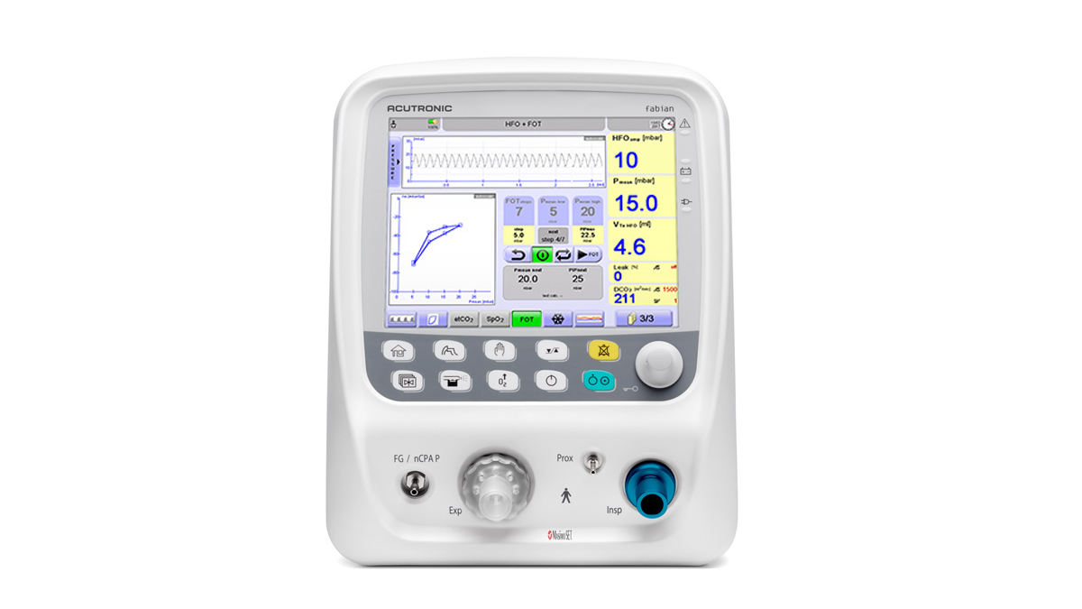 Hvidt medicinsk ventilatorapparat med farvedisplay, knapper og visning af målinger på forsiden.